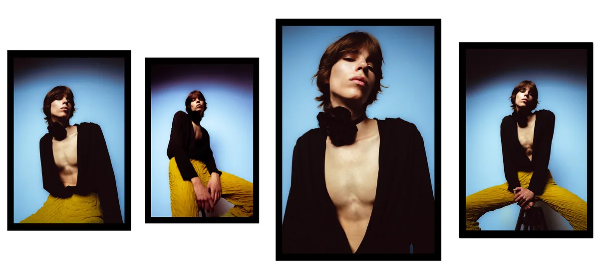 Four low-angle frames of a person in a deep-V black jacket with a black flower at the neck, yellow trousers, blue backdrop