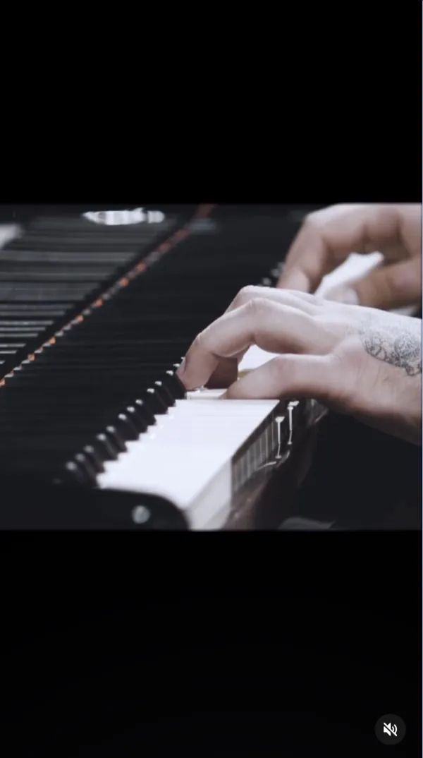 Reel: close-up of hands playing black and white piano keys, a tattoo on the wrist