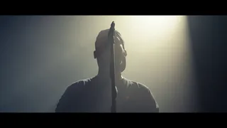 Music video Kortez — Hej Wy: silhouette in a cap behind a mic stand in a hazy spotlight beam