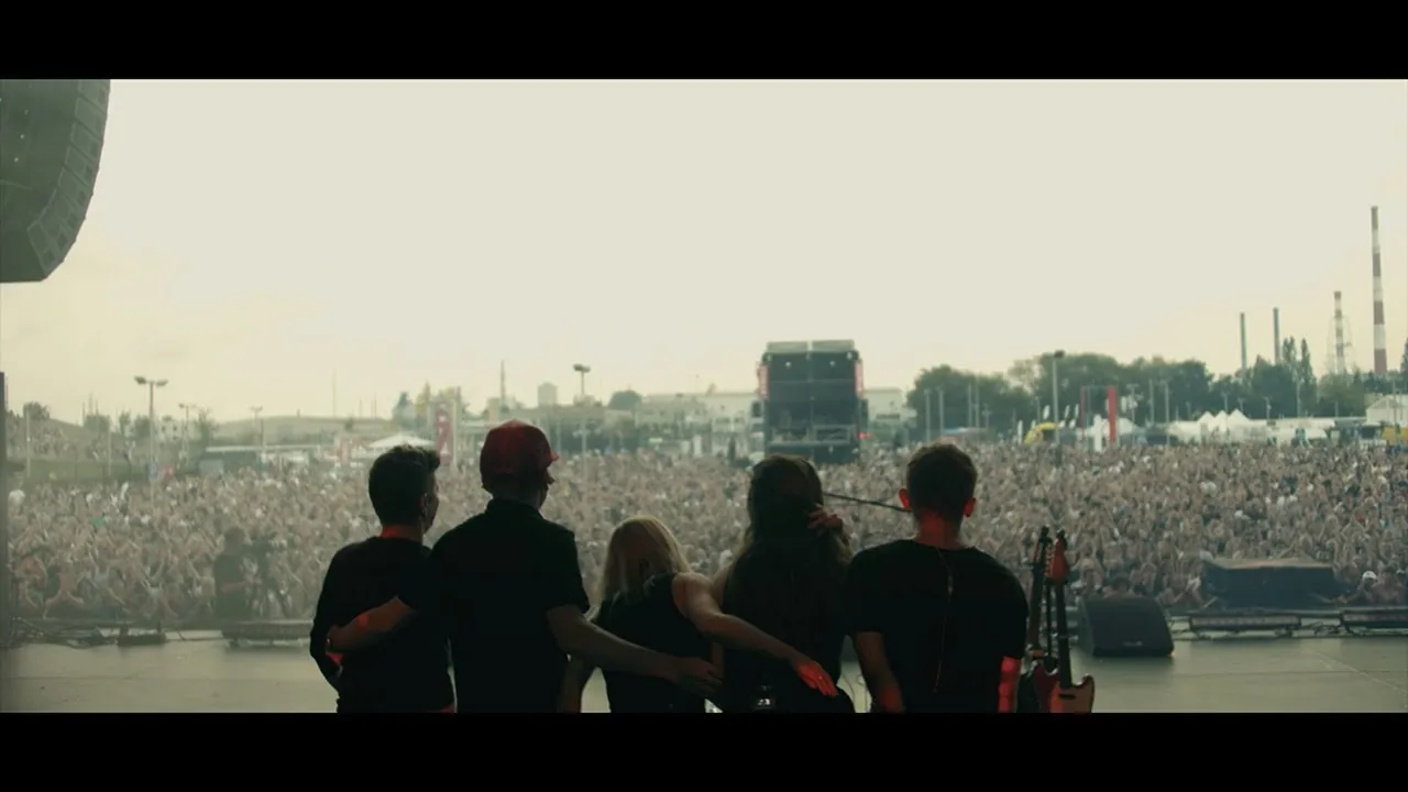 Music video Kaśka Sochacka — 14 minut (film Lato): five people on stage seen from behind, some arm in arm, facing a crowd