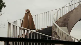 Music video Daria ze Śląska — Nie masz sił to płacz: a person in a brown lace-trimmed cape on a spiral staircase